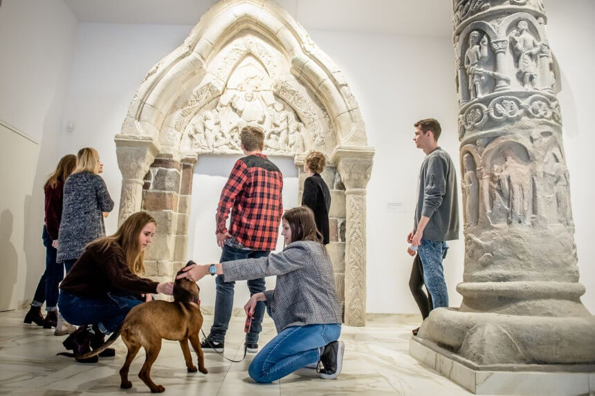 Ludzie i pies zwiedzają wyjątkową kolekcję kilkunastu najważniejszych przykładów romańskich detali architektonicznych z całej Polski (źródło: muzeumgniezno.pl)