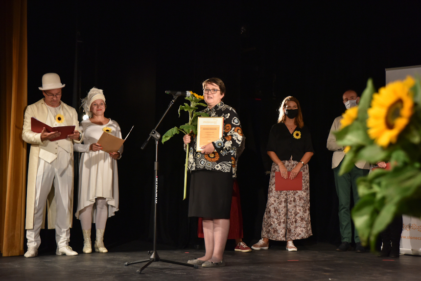 Scena teatru podczas gali wręczania nagród w plebiscycie Słoneczniki 2021. Na środku kobieta, trzymające dyplom i kwiat słonecznika. (źródło: muzhp.pl)