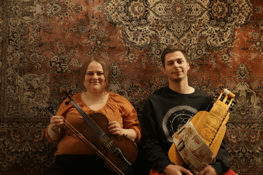 Kobieta (po lewej) ze skrzypcami. Mężczyzna (po prawej) z dawnym instrumentem. Oboje siedzą. Za nimi, na ścianie, arras. (źródło: muzarp.poznan.pl)