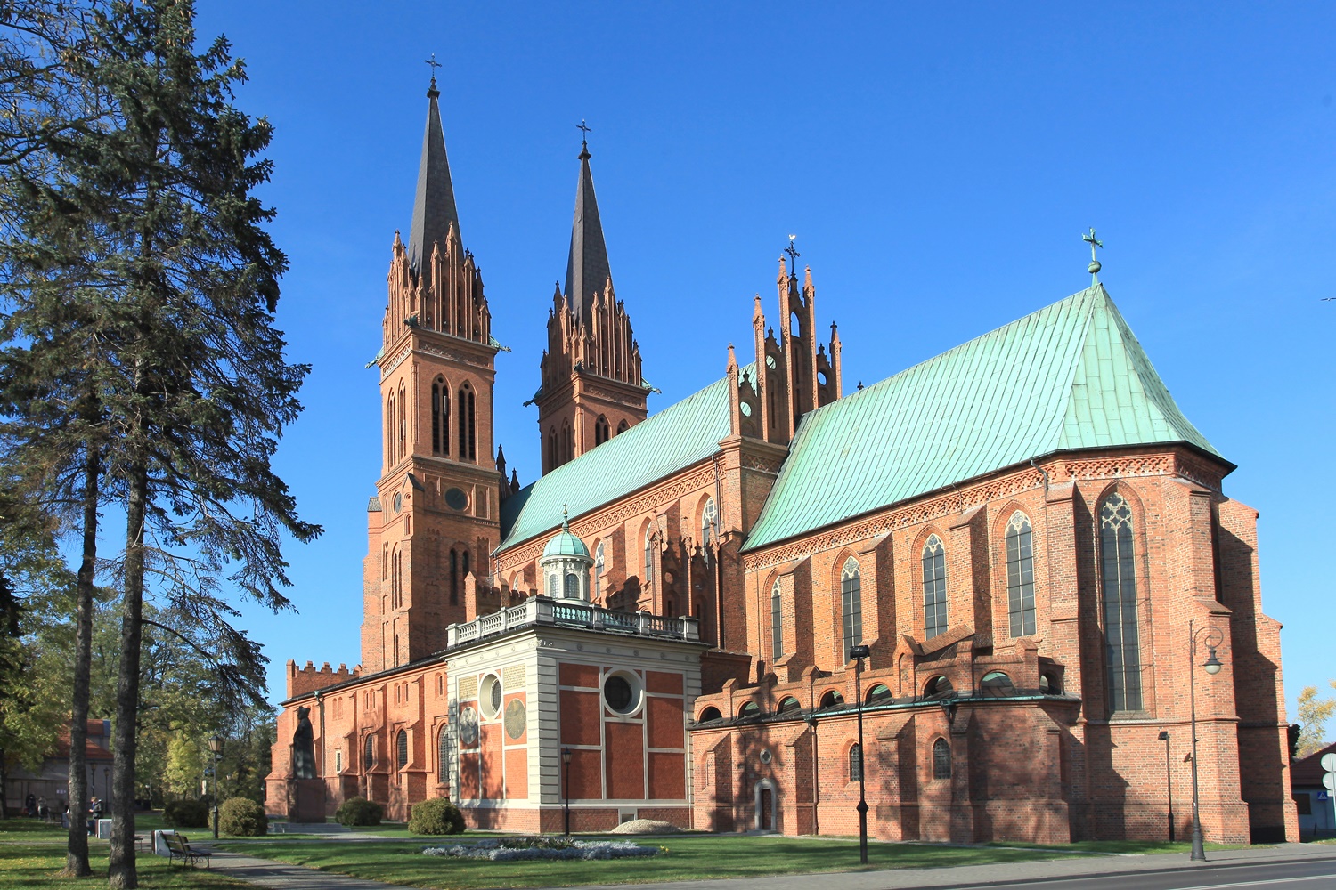 Duży ceglany budynek sakralny - katedra. Z tyłu - dwie strzeliste wierze. pokrycie dachu z zielonej blachy.